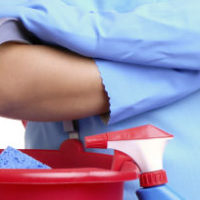 Woman carrying a red pale with a brush inside